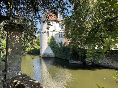 um castelo no meio de um rio com um barco em LES DOUVES, charmante dépendance du château em Crèvecoeur-en Brie