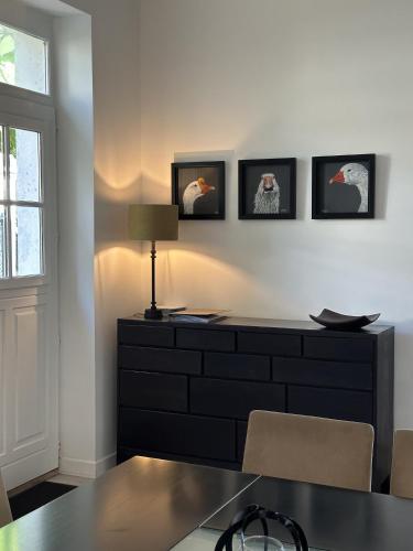 Cette chambre comprend une commode avec une lampe et des photos sur le mur. dans l'établissement LES DOUVES, charmante dépendance du château, à Crèvecoeur-en Brie