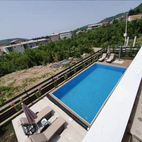 a swimming pool on top of a building with chairs at lux apartmani Porte Nouva in Sutomore