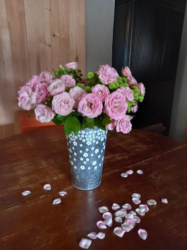 a vase of pink roses on a table with seashells at Vastseliina Metskond Camping in Vahtseliina