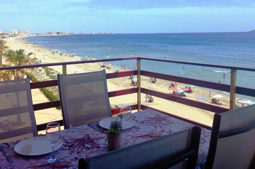 Apartamento primera línea La Manga في لا مانغا ذيل مار مينور: طاولة مع كؤوس للنبيذ وإطلالة على الشاطئ