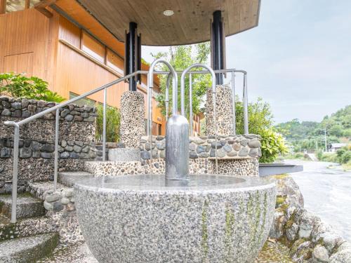 a stone fountain in front of a building at Kur Park Nagayu in Nitta