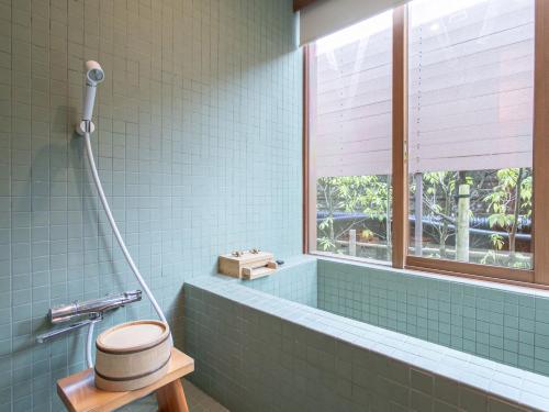 a bathroom with a toilet and a tub and a window at Kur Park Nagayu in Nitta