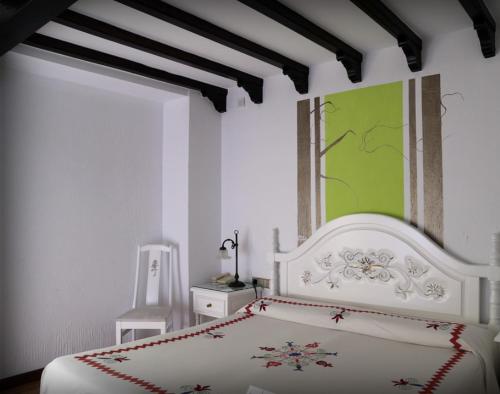a bedroom with a white bed and a green painting at Hotel Doña Teresa in La Alberca
