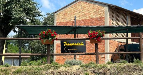 a sign in front of a brick building with flowers at Takápradalù in Cisterna dʼAsti