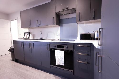 una cocina con armarios grises y horno negro en Chic City Living - Luxury Apartment in London en Hemel Hempstead