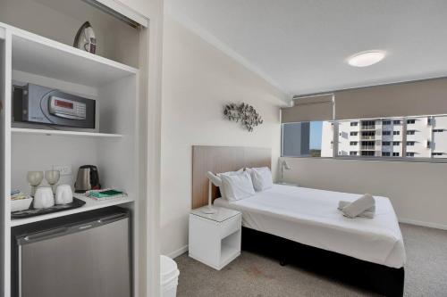 a small bedroom with a white bed and a window at Modern Dual Key Apt w Pool in the heart of Mackay in Mackay