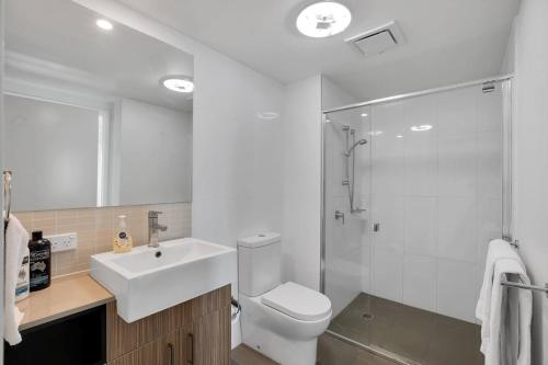 a bathroom with a toilet and a sink and a shower at Modern Dual Key Apt w Pool in the heart of Mackay in Mackay