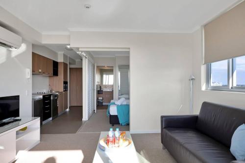 マッカイにあるModern Dual Key Apt w Pool in the heart of Mackayの黒いソファとキッチンのあるリビングルーム