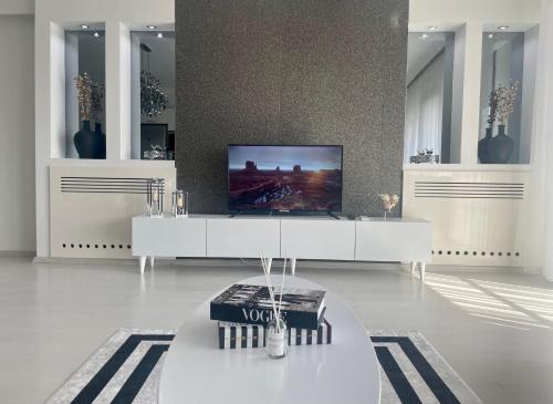 uma sala de estar com uma televisão e uma mesa branca em Kaplan Luxury Flat - 3 Bedrooms with air conditioning & heating in the City em Istambul