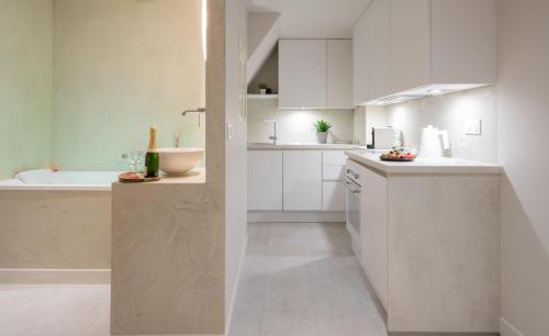uma cozinha branca com armários brancos e um lavatório em Muse old town jacuzzi em Annecy