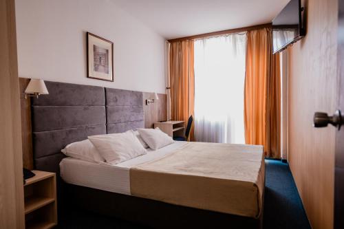 Cama en habitación de hotel con ventana en Hotel Slavija en Belgrado