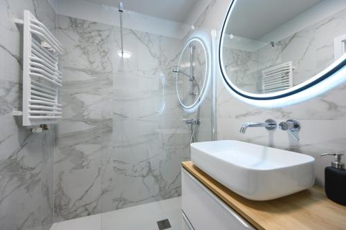 ein weißes Badezimmer mit einem Waschbecken und einem Spiegel in der Unterkunft Apartament Baltic Breeze ProstyWynajem Gdańsk Brzeźno in Danzig