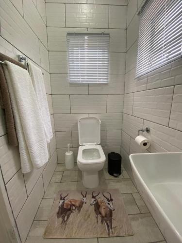 a bathroom with a toilet with three deer on a rug at The Garden Nook in Bloemfontein