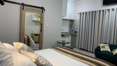a living room with a bed and a kitchen at The Garden Nook in Bloemfontein