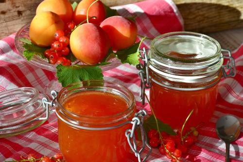 two jars of honey and a bowl of fruit at Les Deux Tilleuls in Sablet