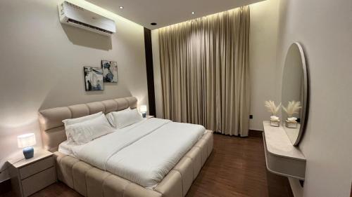 a bedroom with a large white bed and a mirror at Luxury residences in Khamis Mushayt
