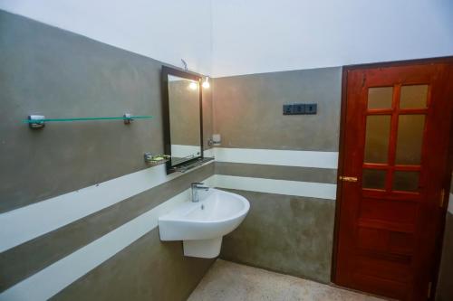 La salle de bains est pourvue d'un lavabo et d'une porte rouge. dans l'établissement Lucky cottage, à Habaraduwa Central