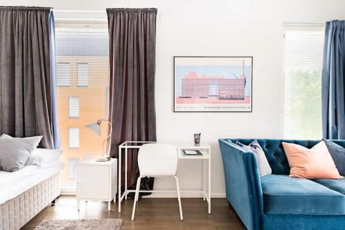 ein Wohnzimmer mit einem blauen Sofa und einem Schreibtisch in der Unterkunft Peaceful Serviced Apartment Tikkurila, near airport, free parking in Vantaa