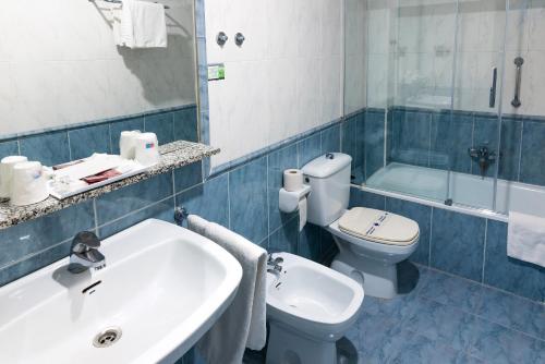 e bagno con lavandino, servizi igienici e vasca. di Hotel San Glorio a Santander