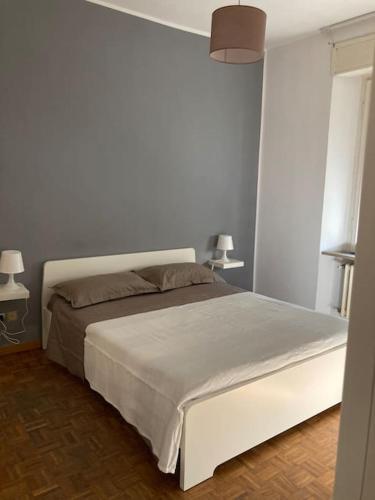 uma cama branca num quarto com 2 candeeiros em Casa Olimpia em Terni