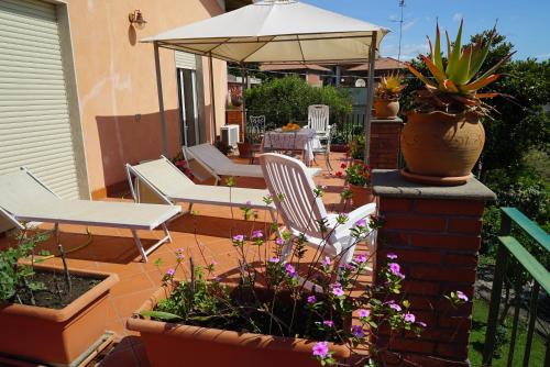 un patio con sillas, flores y una sombrilla en La Magnolia, en Aci Trezza