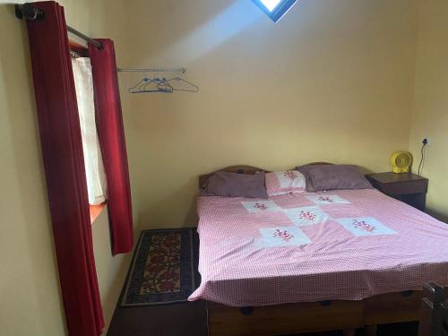 a bedroom with a bed with pink sheets and a window at Kanjira house in Ooty