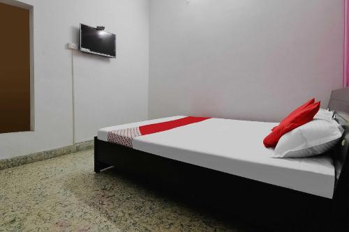 a bedroom with a bed with red and white pillows at OYO Flagship Aashirvaad Green's Guest House in Patna