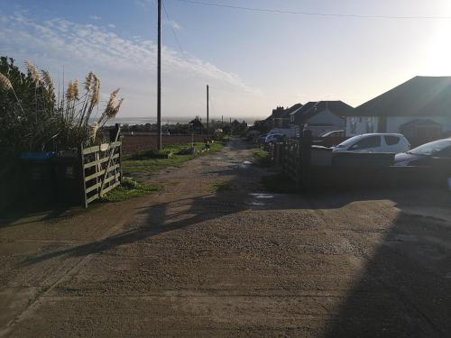 a dirt road with a fence and cars on it at Cedar Top in Manston