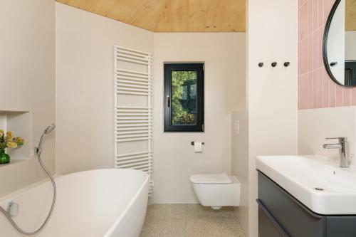 a bathroom with a tub and a toilet and a sink at Elf am See - Haus 10 in Templin