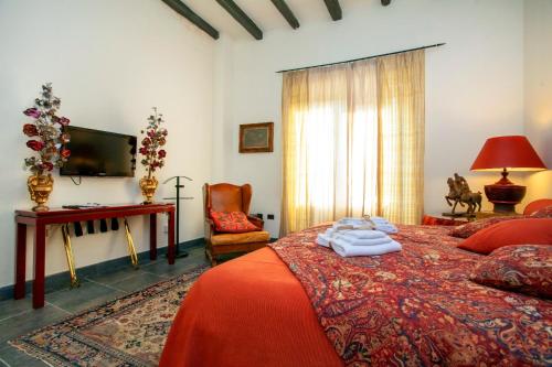 una camera da letto con un letto, una scrivania e una televisione di Borgo Antico XIX sec. a Gesturi