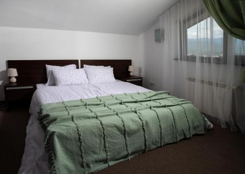 a bedroom with a large bed with a green comforter at Pirin Bliss Apartment Ski, Spa and Relax at Terra Complex in Razlog