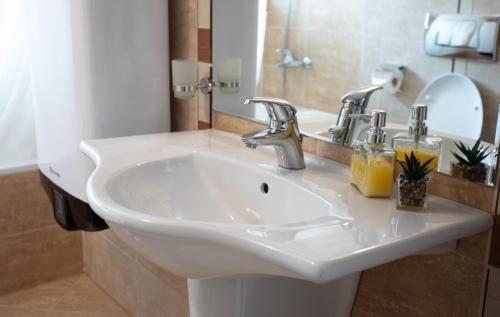 La salle de bains est pourvue d'un lavabo blanc et d'un miroir. dans l'établissement Pirin Bliss Apartment Ski, Spa and Relax at Terra Complex, à Razlog