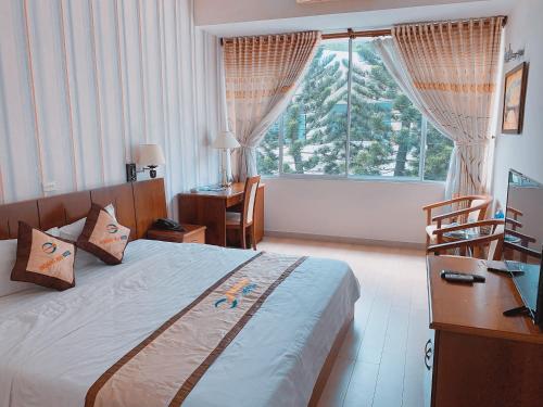 1 dormitorio con cama, escritorio y ventana en Khách Sạn Hoàng Mai Dung Quất, en Bình Sơn