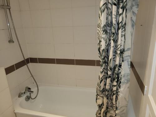 a bath tub with a shower curtain in a bathroom at Noisy Residence in Noisy-le-Grand
