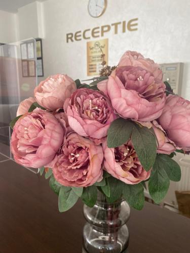 a bouquet of pink flowers in a glass vase at Hotel Parc in Craiova