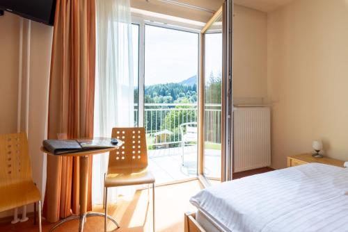 Schlafzimmer mit einem Bett und Blick auf einen Balkon in der Unterkunft Pension Klug Adults only - DorfResort Mitterbach in Mitterbach