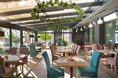 un restaurant avec des tables, des chaises et des fenêtres dans l'établissement Zafír Apartmanház, à Sárvár