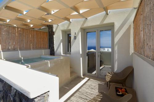 Adorno Oia في أويا: حوض استحمام ساخن في غرفة مطلة على المحيط