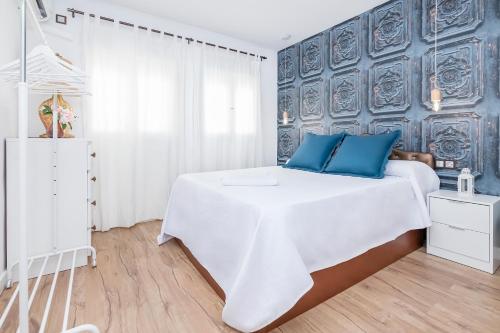 1 dormitorio con 1 cama blanca grande con almohadas azules en BHost - Tendillas, en Córdoba