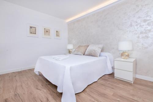 a white bedroom with a bed and a night stand at BHost - Tendillas in Córdoba