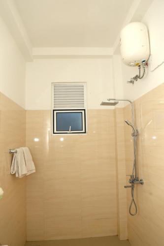 a bathroom with a shower and a window at Sandy Palms Guesthouse in Hikkaduwa