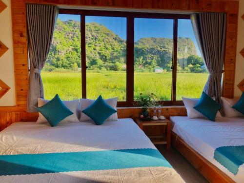 two beds in a room with a view of a field at Rosa Garden in Ninh Binh