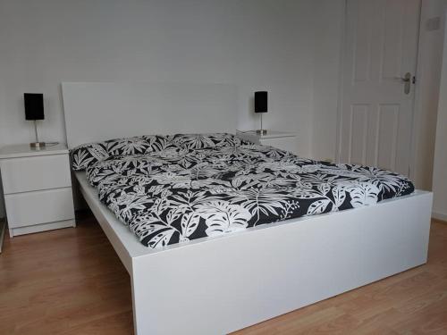 a white bed with a black and white blanket on it at Private 2 Bed Flat close to EXCEL & CITY AIRPORT in London