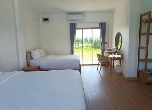 een hotelkamer met 2 bedden, een tafel en een bureau bij Guest House Blue Andaman in Phra Ae beach