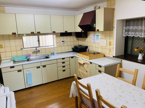 uma cozinha com armários brancos, uma mesa e um lavatório em homelike / Vacation STAY 33817 em Chiba
