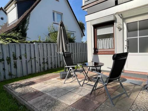 2 Stühle, ein Tisch und ein Sonnenschirm auf einer Terrasse in der Unterkunft An der Allee 7 App in Dahme