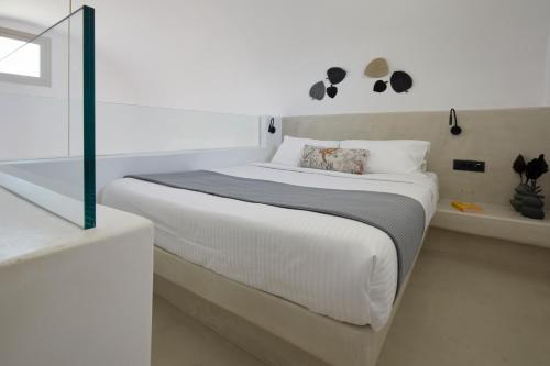 a white bedroom with a bed and a bath tub at Adorno Oia in Oia