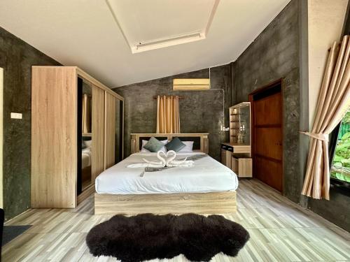 een slaapkamer met een groot bed met een zwarte muur bij Rai Phusaitran ไร่ภูสายธาร in Mae Taeng