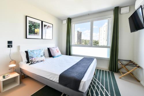 a bedroom with a bed and a large window at Student Factory Toulouse Zénith in Toulouse